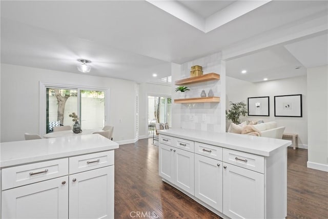 kitchen featuring open floor plan, light countertops, dark wood finished floors, and white cabinetry