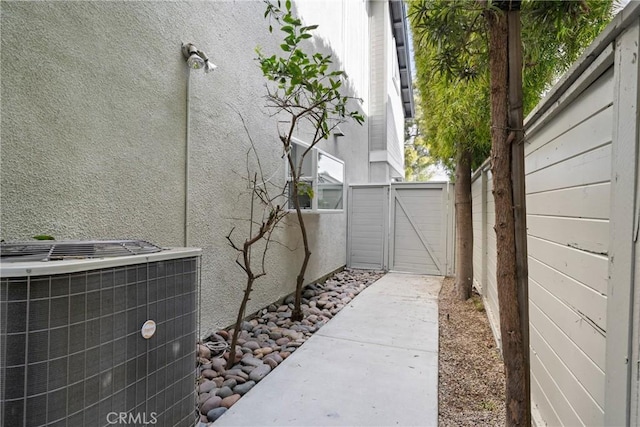 view of side of property with a gate, fence, and central AC