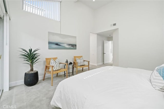 bedroom with baseboards, a high ceiling, visible vents, and light colored carpet