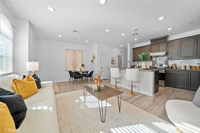 living room featuring recessed lighting, visible vents, and light wood-style flooring