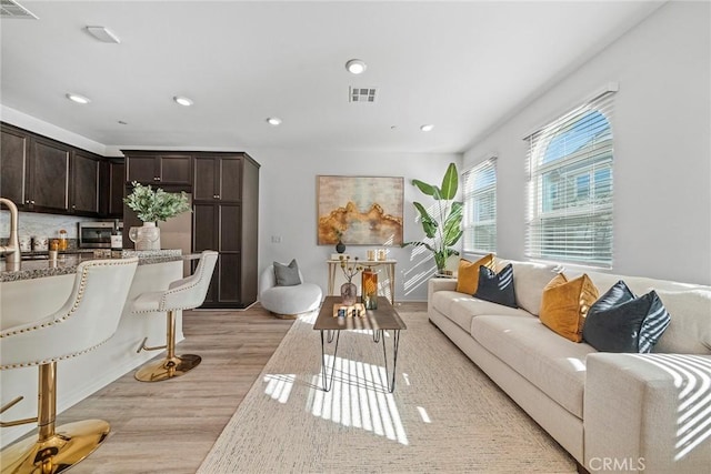 living area with light wood-style floors, recessed lighting, and visible vents