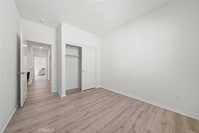 unfurnished bedroom featuring baseboards, a closet, and light wood-style floors