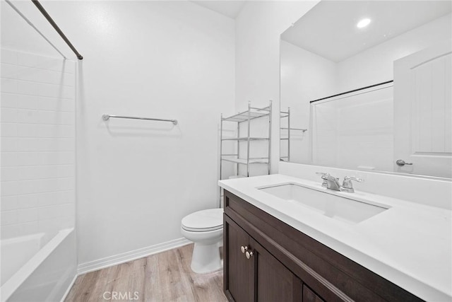 full bath featuring toilet, tub / shower combination, vanity, wood finished floors, and baseboards