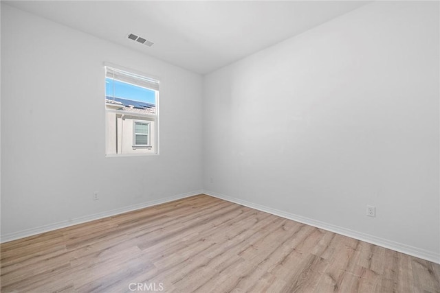 spare room with baseboards, visible vents, and light wood-style floors