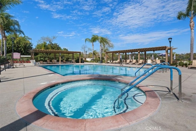 pool with a hot tub, a pergola, and a patio