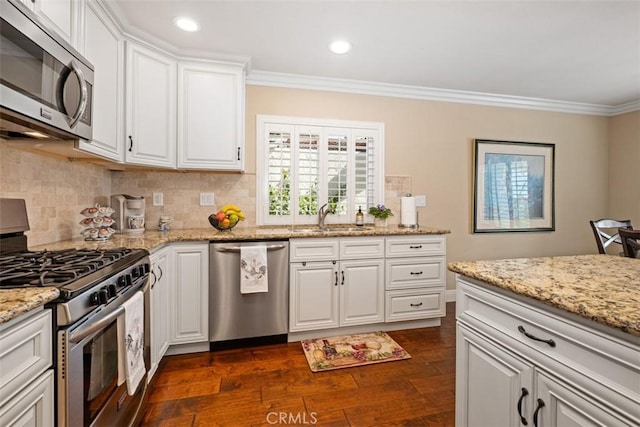 kitchen featuring decorative backsplash, dark wood-style floors, ornamental molding, stainless steel appliances, and a sink