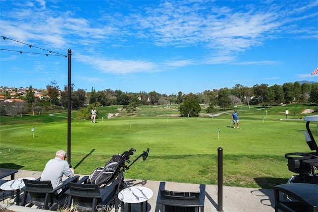 surrounding community with golf course view and a lawn