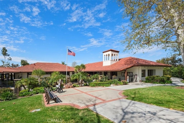 back of house featuring driveway, a yard, a tiled roof, and stucco siding