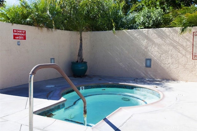 view of pool featuring a community hot tub and a fenced backyard