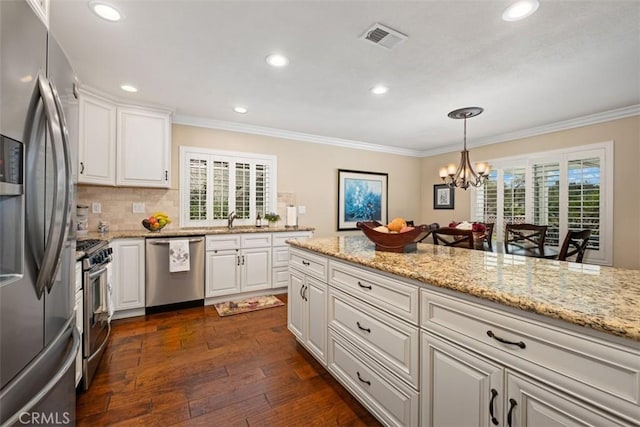 kitchen with ornamental molding, appliances with stainless steel finishes, plenty of natural light, and visible vents