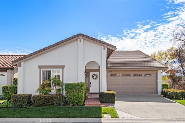 view of front of house with a garage, concrete driveway, a tiled roof, and stucco siding