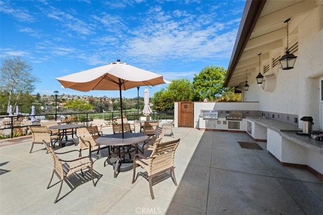 view of patio with a sink, outdoor dining area, an outdoor kitchen, and a grill