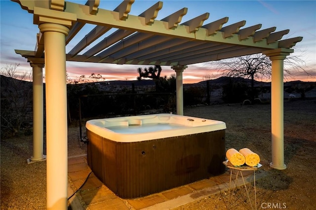 patio terrace at dusk with a pergola and a hot tub