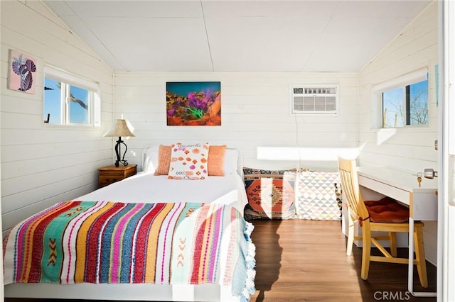 bedroom featuring lofted ceiling, multiple windows, and a wall mounted air conditioner