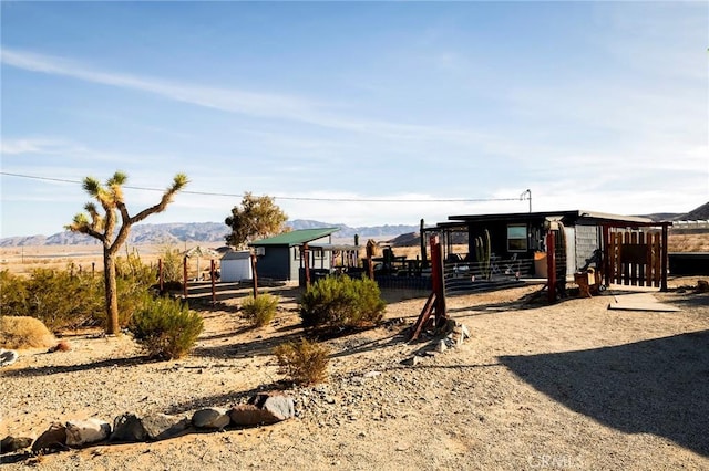 view of jungle gym featuring fence, a mountain view, and an outbuilding