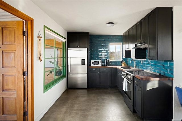 kitchen featuring under cabinet range hood, a sink, finished concrete flooring, appliances with stainless steel finishes, and backsplash