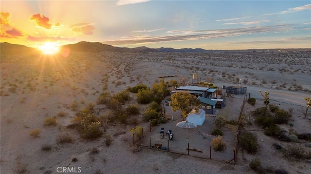 aerial view at dusk featuring a mountain view and a desert view