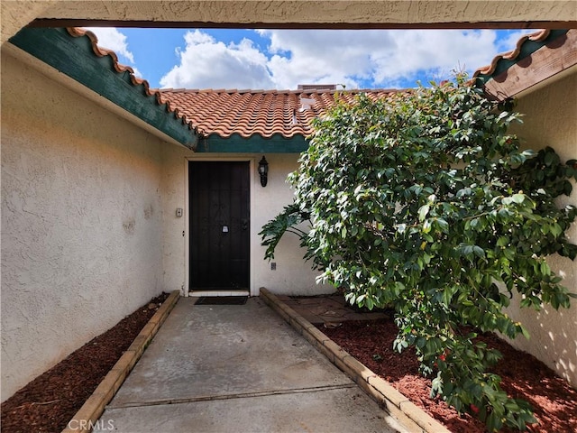 property entrance featuring stucco siding and a tiled roof