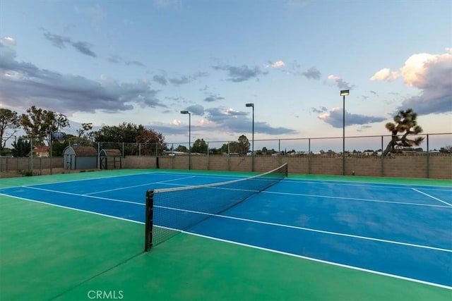 view of sport court featuring a storage shed and fence