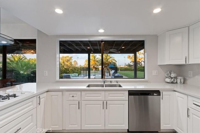 kitchen featuring recessed lighting, light countertops, stainless steel dishwasher, white cabinets, and a sink