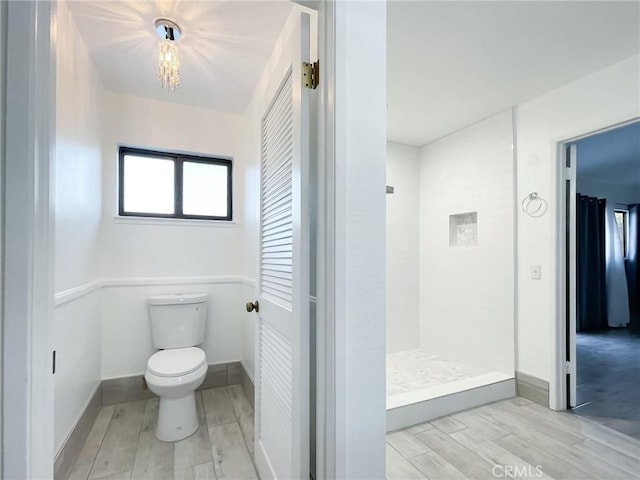 full bathroom featuring a walk in shower, wood finished floors, toilet, and baseboards