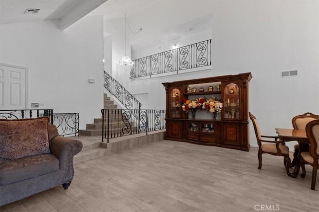 living room featuring a notable chandelier, wood finished floors, visible vents, stairs, and beamed ceiling