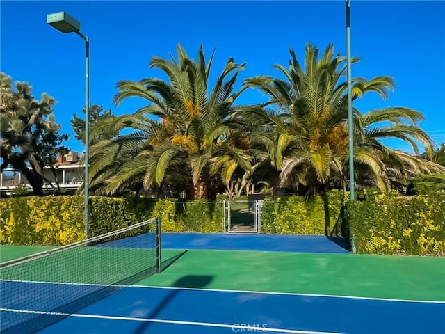 view of tennis court featuring a gate and fence