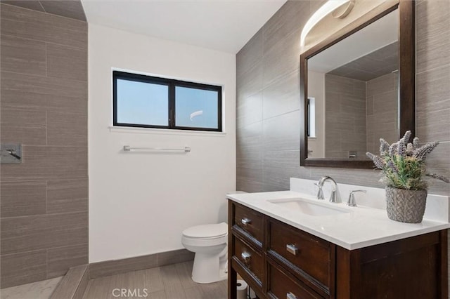 full bathroom with toilet, vanity, and tile walls