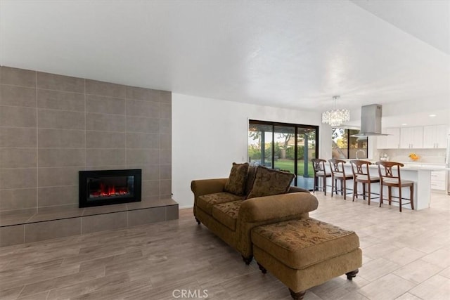 living room featuring a chandelier, a tile fireplace, and light wood-style flooring