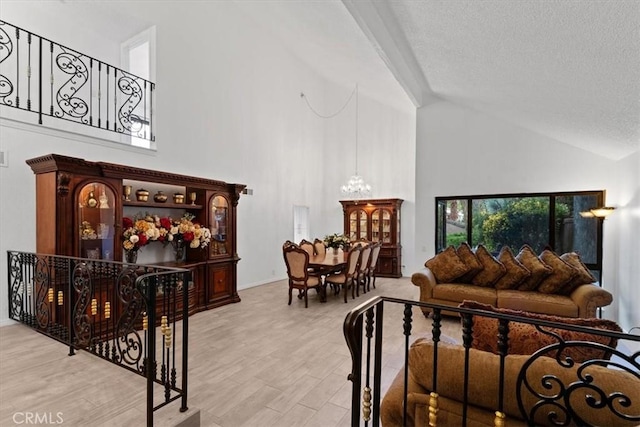 living room with high vaulted ceiling, a notable chandelier, a textured ceiling, and wood finished floors