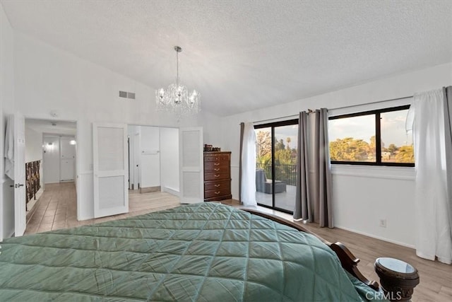 bedroom featuring access to exterior, lofted ceiling, visible vents, light wood-style floors, and a textured ceiling