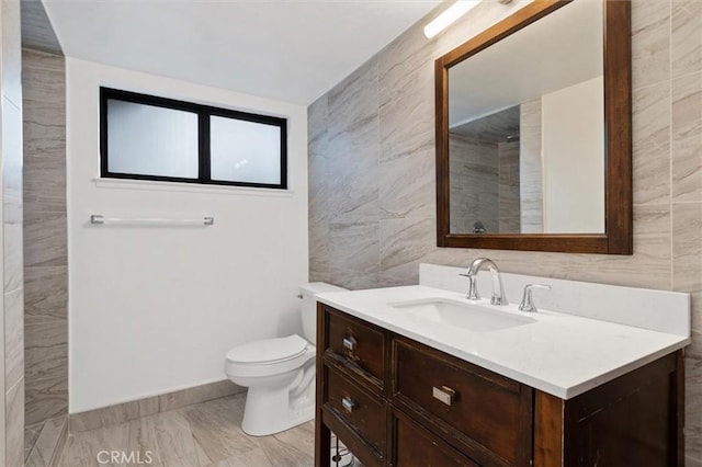 bathroom with toilet, tile walls, and vanity