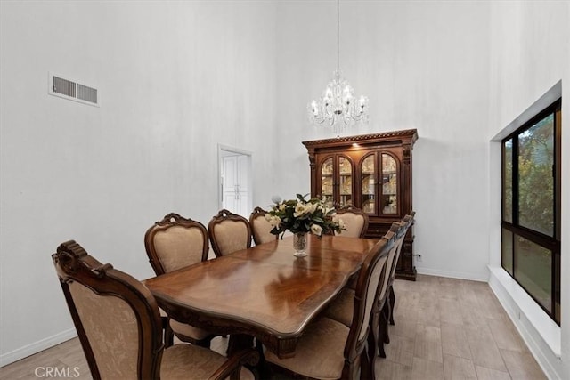 dining area with a chandelier, a high ceiling, visible vents, and baseboards