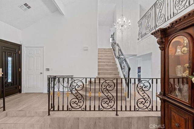 interior space with high vaulted ceiling, visible vents, stairs, beam ceiling, and an inviting chandelier