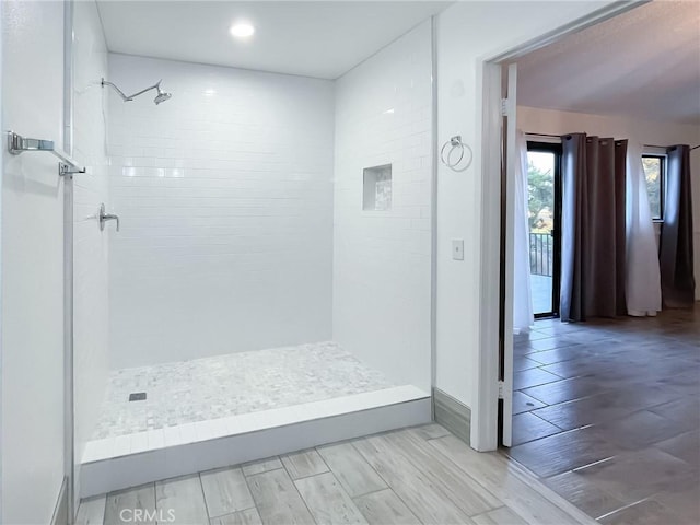 bathroom with wood finish floors and tiled shower