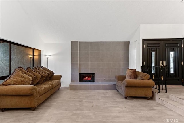 living room featuring light wood finished floors, a fireplace, and vaulted ceiling