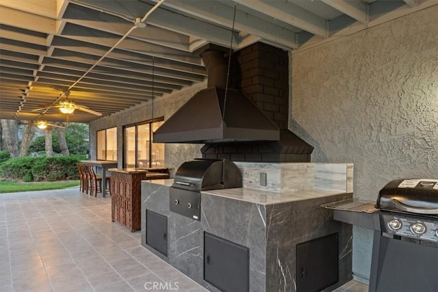 view of patio with exterior kitchen and a grill