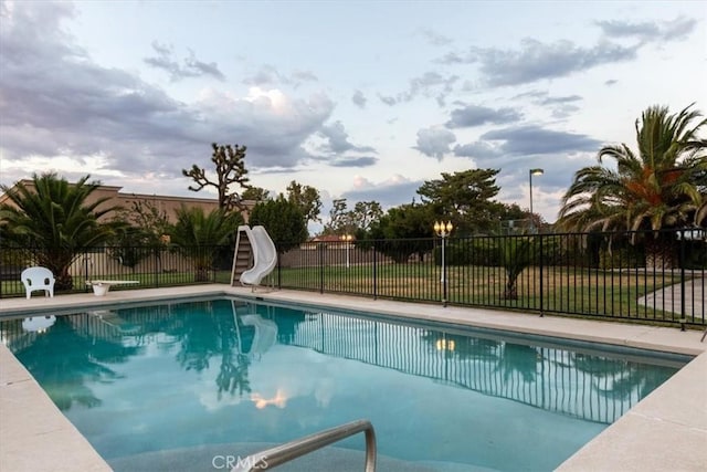 view of swimming pool featuring a fenced in pool, a water slide, and fence