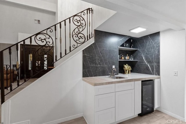 bar with wine cooler, visible vents, stairway, a sink, and wet bar