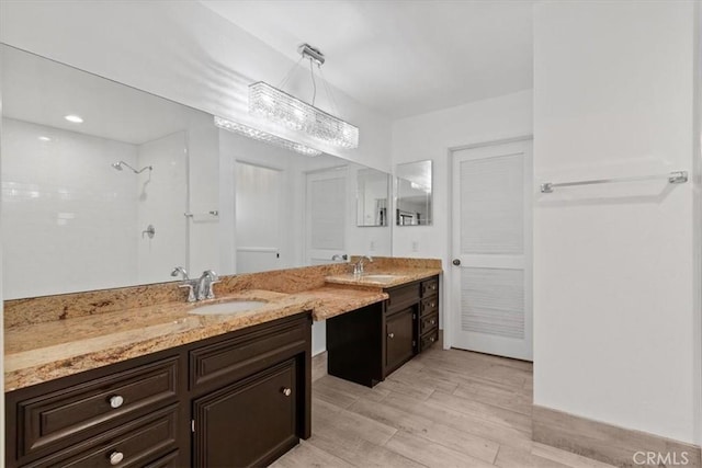 full bath featuring a tile shower, wood finished floors, and vanity