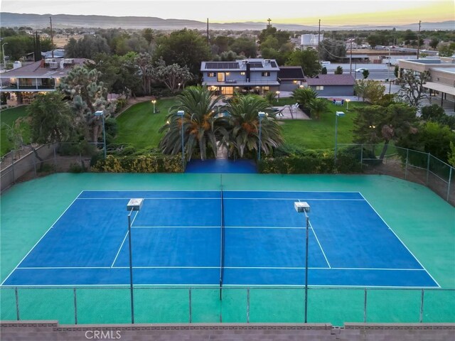 view of tennis court with fence and a mountain view