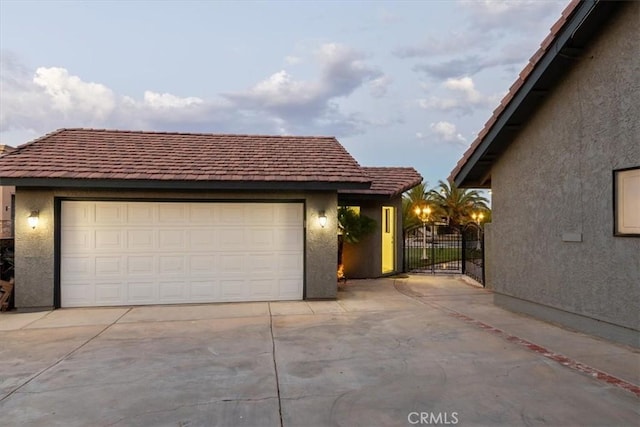 view of front of property with a garage, an outbuilding, a gate, and stucco siding