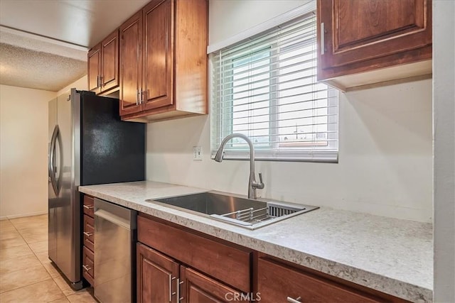 kitchen with light countertops, stainless steel dishwasher, light tile patterned flooring, a sink, and a textured ceiling