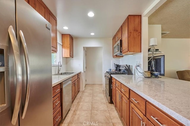 kitchen featuring brown cabinetry, light tile patterned floors, stainless steel appliances, and a sink