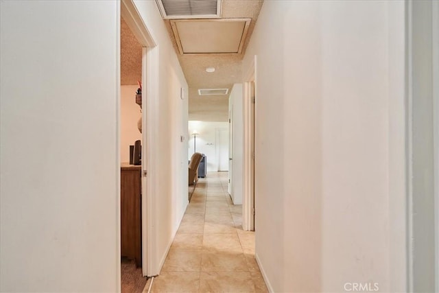 corridor featuring attic access, visible vents, and light tile patterned floors