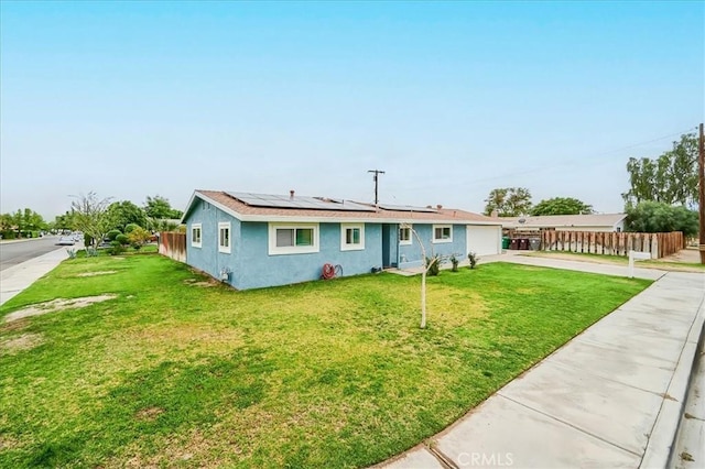 ranch-style home featuring solar panels, fence, concrete driveway, stucco siding, and a front yard