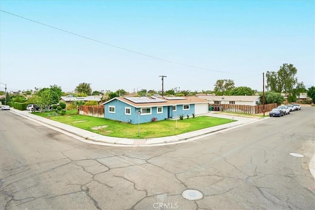 single story home with stucco siding, fence, a front lawn, and solar panels