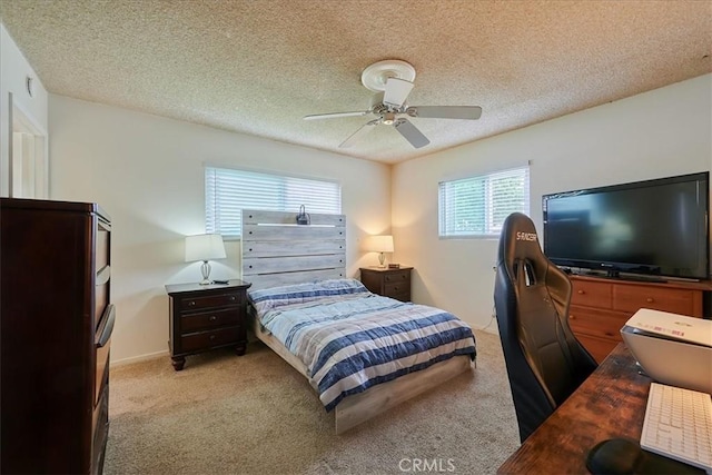 bedroom featuring light carpet, ceiling fan, baseboards, and a textured ceiling