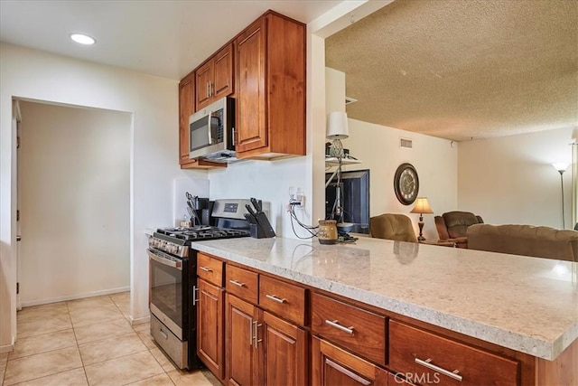 kitchen featuring open floor plan, a peninsula, appliances with stainless steel finishes, and brown cabinets