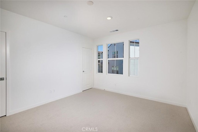 unfurnished room with visible vents, recessed lighting, baseboards, and light carpet